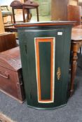 A painted bow fronted corner cabinet