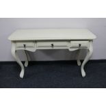 A cream painted three drawer dressing table