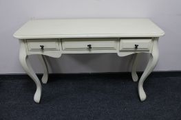 A cream painted three drawer dressing table