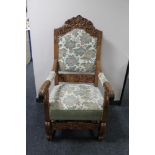 A heavily carved oak armchair with floral tapestry covering