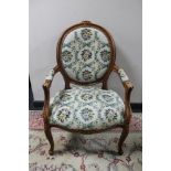 A carved walnut armchair with floral tapestry covering