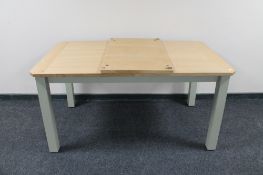 A contemporary oak topped pull out table on painted legs