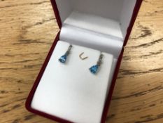 A pair of blue topaz and diamond earrings set with diamonds.