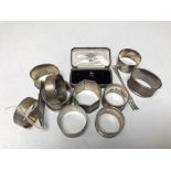 A group of ten assorted silver napkin rings together with a silver pickle fork and a Gent's yellow
