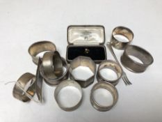 A group of ten assorted silver napkin rings together with a silver pickle fork and a Gent's yellow