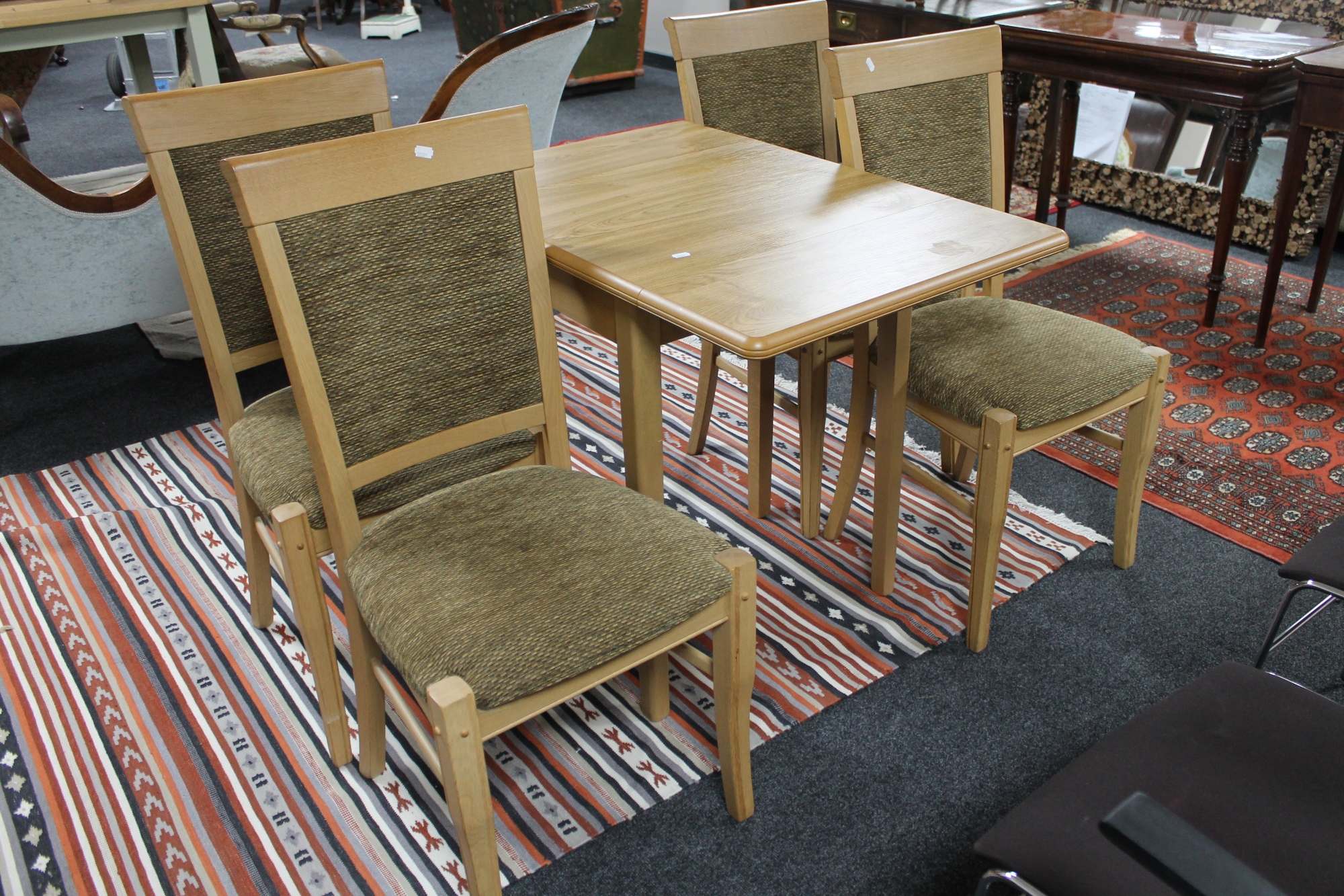 A contemporary dining room table together with four chairs in light oak finish