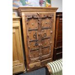 A uniquely carved oak cabinet with metal adornments