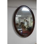 A mahogany oval framed bevelled mirror