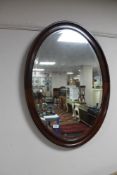 A mahogany oval framed bevelled mirror