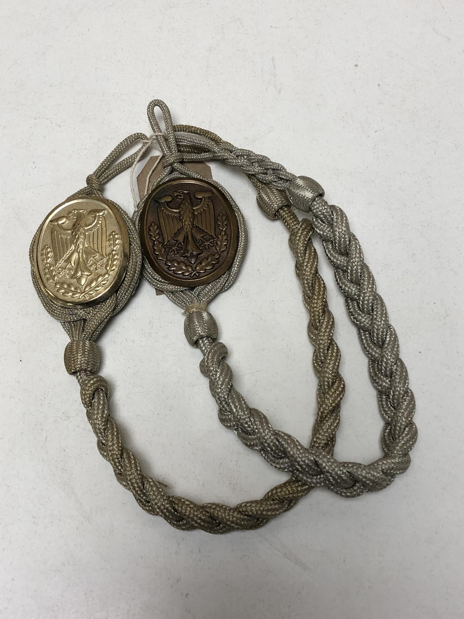 Two reproduction German military badges on braid