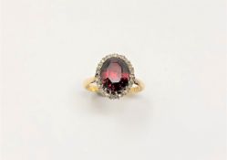 An 18ct gold oval garnet ring on yellow gold shank set with diamonds, size Q, 5.9g.