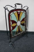 An antique stained glass metal fire screen