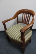 A mid 20th century heavy oak armchair in green striped fabric