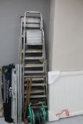 Two metal step ladders together with a quantity of garden tools, aluminium roll up table,