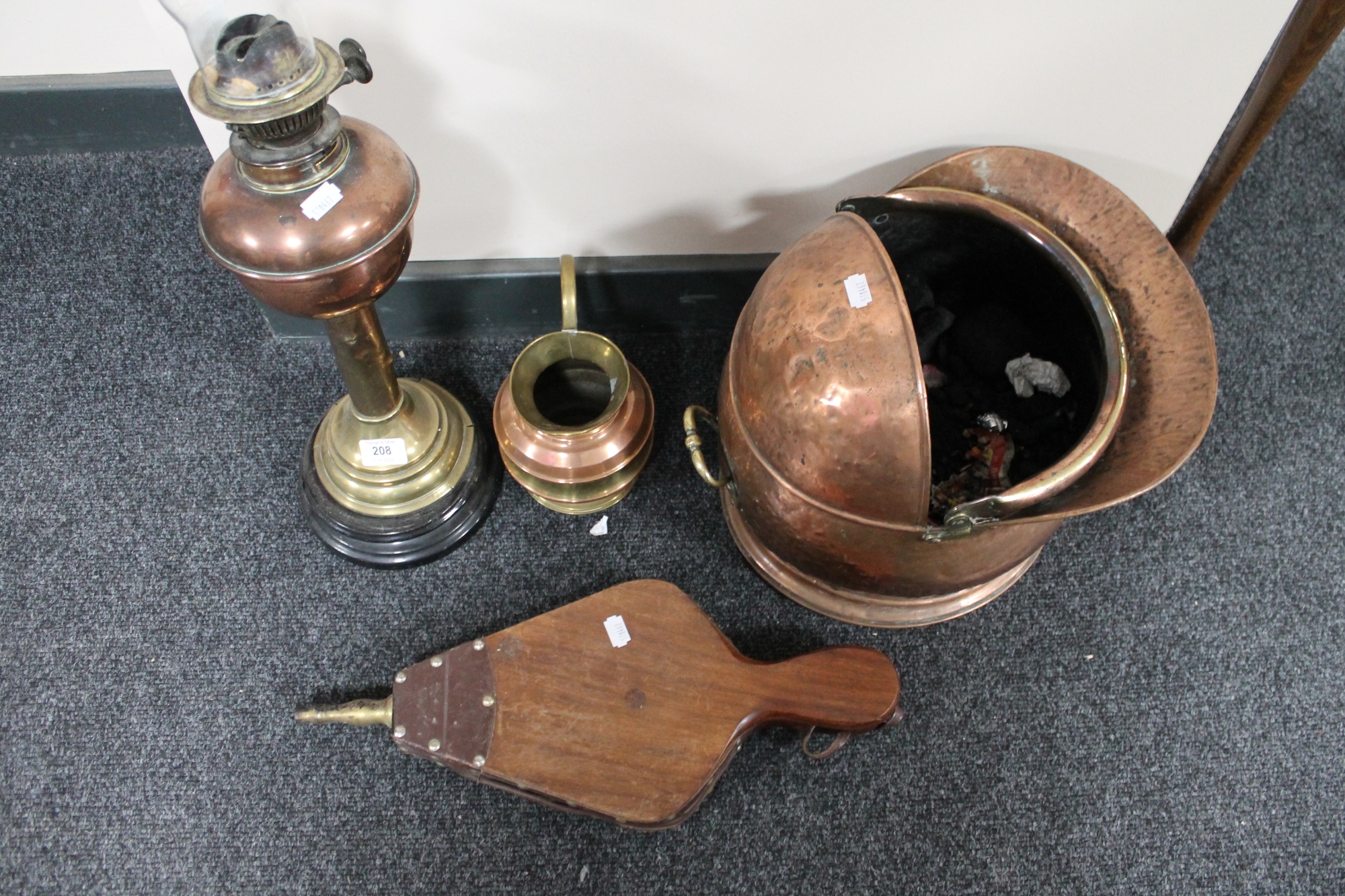 An antique brass and copper oil lamp together with copper coal helmet,