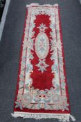 A fringed Chinese carpet runner on red ground together with a matching blue unner.