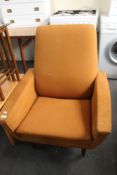 A mid century orange fabric armchair.