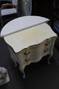 A white and gilt two drawer chest and a white d-shaped table.