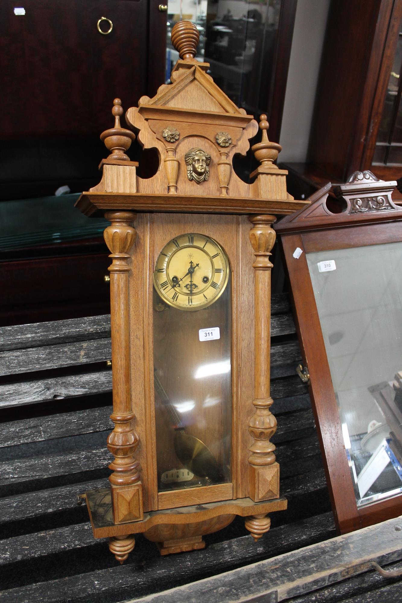 A continental oak wall clock with pendulum and key
