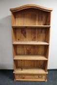 A pine bookcase fitted with a drawer