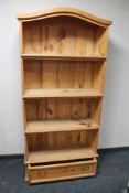 A pine bookcase fitted with a drawer