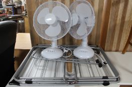 A pair of table fans together with clothes airier