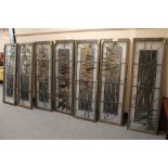 A series of seven stained glass wooden framed panels with abstract leaf design,
