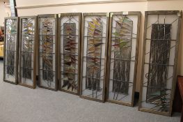 A series of seven stained glass wooden framed panels with abstract leaf design,