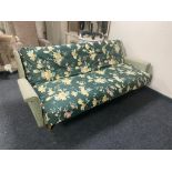 A mid century day bed with green floral covering