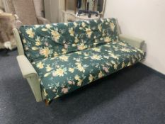 A mid century day bed with green floral covering
