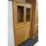 A light oak display cabinet fitted with a drawer