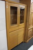 A light oak display cabinet fitted with a drawer