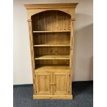 A pine bookcase fitted with double cupboard below