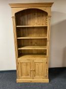 A pine bookcase fitted with double cupboard below