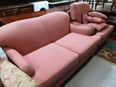 An antique style two seater settee and armchair upholstered in pink with scatter cushions