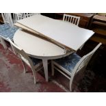 A painted white extending dining table, with three leaves and four dining chairs.