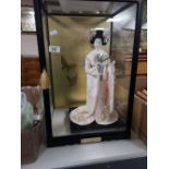 A decorative Geisha figure in display cabinet