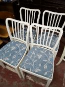 Four painted white dining chairs with seats in floral fabric.