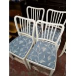 Four painted white dining chairs with seats in floral fabric.