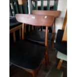 A pair of teak dining chairs.