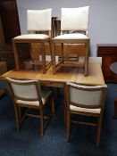A light oak flap sided dining table together with six cream studded leather chairs