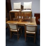 A light oak flap sided dining table together with six cream studded leather chairs