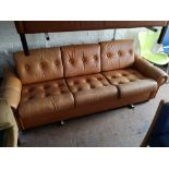 A Scandinavian brown leather two seater studded settee.