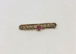 A 9ct gold seed pearl bar brooch set with a ruby coloured stone, 3.6g.
