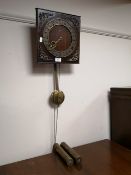 A mid century continental wall clock with pendulum and two weights
