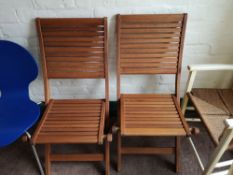 A pair of teak folding garden chairs.