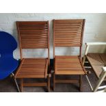 A pair of teak folding garden chairs.