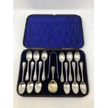 A Victorian cased set of twelve silver spoons, tongs and matching caddy spoon.
