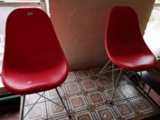 A pair of red contemporary chairs with metal under stretchers.