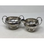 A hammered-silver cream jug and matching sugar basin,
